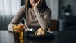 © Risat Designer - A woman sits at a table, looking bored and uninspired while picking at a single piece of cauliflower on her plate with a fork, symbolizing dieting struggles.