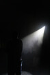© Mareks - Silhouette of a Man Standing Alone on a Dark Stage Under a Single Dramatic Spotlight