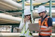 © BESTIMAGE - Male and female petroleum engineers in safety uniform pointing while discussing about maintenance project under oil pipeline system at fuel refinery plant engineering teamwork energy industry.
