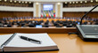 © val_webart - Conference table with notebook and pen in debate chamber setting