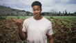 © Krakenimages.com - African american man pointing thumb over shoulder with bare hand while wearing pale pink t shirt in forest; casual confidence.