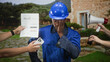 © Krakenimages.com - Man construction worker in blue hardhat with hand on cheek as megaphone, smartphone and report are thrust at him by others outside a building; stress pressure.
