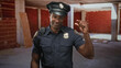 © Krakenimages.com - Man police officer in uniform points finger upward inside an empty brick building, radio mic on shoulder and badge visible; duty.