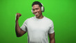 © Krakenimages.com - Black man wearing headphones flexes right bicep and smiles toward camera in green screen studio while wearing white t shirt; confidence groove.