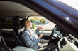 © Davor - Mature driver applying lip balm with smartphone in a parked car
