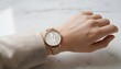 © antuanetto - Close up of a woman adjusting her rose gold watch on her wrist over a marble surface for a time management and elegant lifestyle concept with minimalist lighting