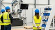 © realis - Diverse factory workers in hard hats and safety vests observe a robotic arm and equipment in