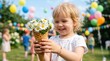 © Lisicus - Smiling girl holding waffle cone filled with daisies at outdoor party. Summer celebration concept for kids birthday events and family gatherings