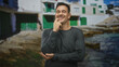 © Krakenimages.com - Handsome hispanic man with moustache finger to lips smiling with eyes closed in front of coastal building; amused ease.