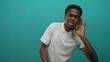 © Krakenimages.com - Man with hand to ear listening gesture in turquoise studio wearing white polo shirt and glasses; curiosity.