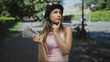 © Krakenimages.com - Young woman holding cash and hand on chin in street wearing bicycle helmet; contemplative wealth choice.