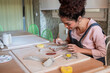© ADDICTIVE STOCK - Young woman shaping clay pieces at a pottery workshop table