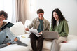 © ADDICTIVE STOCK - Young adult friend group studying on sofa with laptop