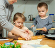 © JackF - Mother and her two sons roll out pizza dough together during fun family cooking activity