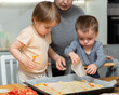© JackF - Toddler girl and boy cook pizza with mom in kitchen. Children help mother, they are passionate about kitchen chores, learning through practical work..