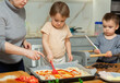 © JackF - Mother and her two sons roll out pizza dough together during fun family cooking activity