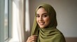 © Andres Mejia - Beautiful Young Muslim Woman in Green Hijab Smiling Confidently by a Window with Natural Light
