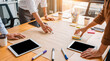 © Jonathan - Creative business team brainstorming ideas, writing on large paper with markers and using digital tablets.