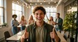 © AFFANYUDA - Excited Young Man Giving Thumbs Up in Modern Office with Diverse Team.