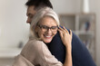 © fizkes - Older mom in glasses enjoy moment of tenderness with young adult son, cuddling tightly, standing together indoors, relish reunion after long separation, smiling, glad to see each other, express caress