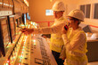 © Nutchapong Wuttisak - Male and female engineers analyzing data at control panel in power plant, supporting clean energy management, system control and advanced industrial engineering concept