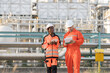 © amorn - Oil refinery or Petroleum refinery. Gas pipeline network system at the industrial estate area. Petrochemical engineer in safety gear working, discussing of work at petrochemical industrial estate