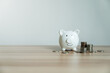 © Thanadon88 - White piggy bank smiles softly on wooden surface. Coins scattered nearby hint at savings and growth. Minimalist background lets focus remain on financial theme. Ideal for budgeting, finance