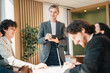© chokniti - Business team meeting discussion collaboration presenting data analysis corporate teamwork diverse professionals planning strategy office communication partnership