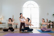 © Ekkasit A Siam - Asian female trainer guides young women friend group through seated yoga twist, bright studio class, wellness routine, posture alignment, gentle stretching, calm motivation, indoor fitness coaching