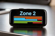 © troyanphoto - Fitness tracker display showing Zone 2 cardio training bars on dark desk