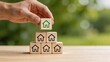 © Wei - Business man hand stacking wooden cubes with house icons symbolising real estate investment property development strategy green building initiatives eco friendly housing solutions