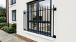 © TaninTanha - Modern black wrought iron window security railing on beige house wall | Contemporary residential architectural exterior detail with metal bars | Home window safety and protection design features