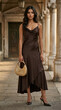 © Arif - Elegant young woman in brown satin midi dress holding handbag, luxury fashion street style.