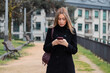 © carballo - young woman walking down the street with a mobile phone