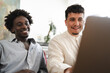 © Studio Marmellata - Two young men smile while looking at a laptop screen together, sharing a moment of collaboration or entertainment.