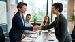© Vyacheslav - business partnership and successful agreement meeting, Two business women shake hands across office table during meeting. Colleagues sit in background with notes. Bright modern workspace. Partnership