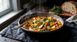 © Simone Matos - A steaming bowl of hearty vegetable soup garnished with fresh herbs served on a rustic wooden table