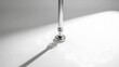 © irawan - Elegant chrome faucet casting a long shadow on a pristine white surface, minimalist design.