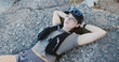 © peopleimages.com - Tired, woman and relax for fitness on rocks from exercise, intense training and recovery. Thinking, female person or exhausted with fatigue, athlete burnout and break in nature from challenge