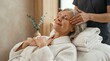 © Kristina - Senior woman receiving professional facial massage from therapist in luxury spa. Relaxed caucasian female client enjoying wellness treatment. Anti aging skincare and rejuvenation concept.