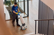 © Drazen - Janitor using professional floor scrubbing machine while cleaning corporate office lobby.