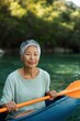 © Andrii Zastrozhnov - Older woman holding paddle while seated in kayak on lake near forest shore