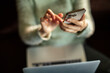 © Davor - Person using smartphone while working on laptop at home