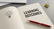 © Mahmuda - educational assessment and learning outcomes concept | academic success and student performance goals | notebook with learning outcomes text and lightbulb icon | corporate training objectives
