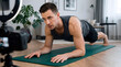 © Александр Марченко - Male fitness influencer recording workout tutorial on yoga mat at home