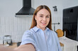 © Valerii Honcharuk - Cheerful woman in blue shirt taking selfie in bright modern kitchen