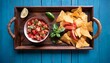 © Nicholas - flat lay overhead view of fresh homemade salaa made with organic tomatoes and basil in a vintage bowl and organic corn chips on an antique wooden tray