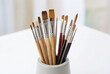 © Meow Creations - Collection of various artist paint brushes in a holder on a white table