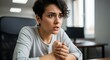 © Nina - Young woman with anxious expression sitting at office desk feeling stressed and overwhelmed