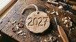 © LenaLensLife - Wooden 2027 ornament on workbench, handcrafted carving in rustic workshop setting with tools and shavings